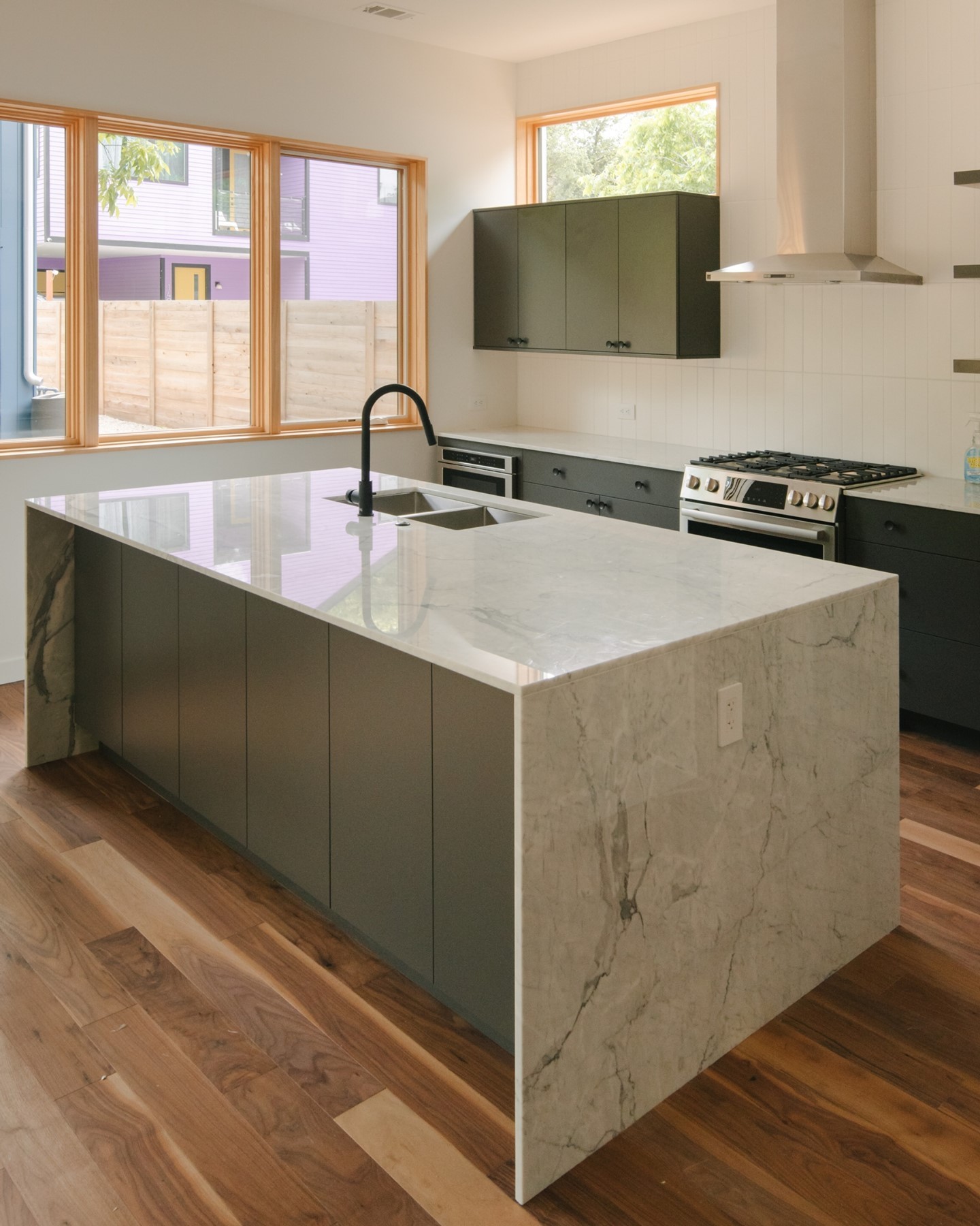 Between its marble island, dark cabinetry, and natural wood flooring, this kitchen represents the perfect amount of balance. ⚖️⁠
⁠
Photo: @caseychap